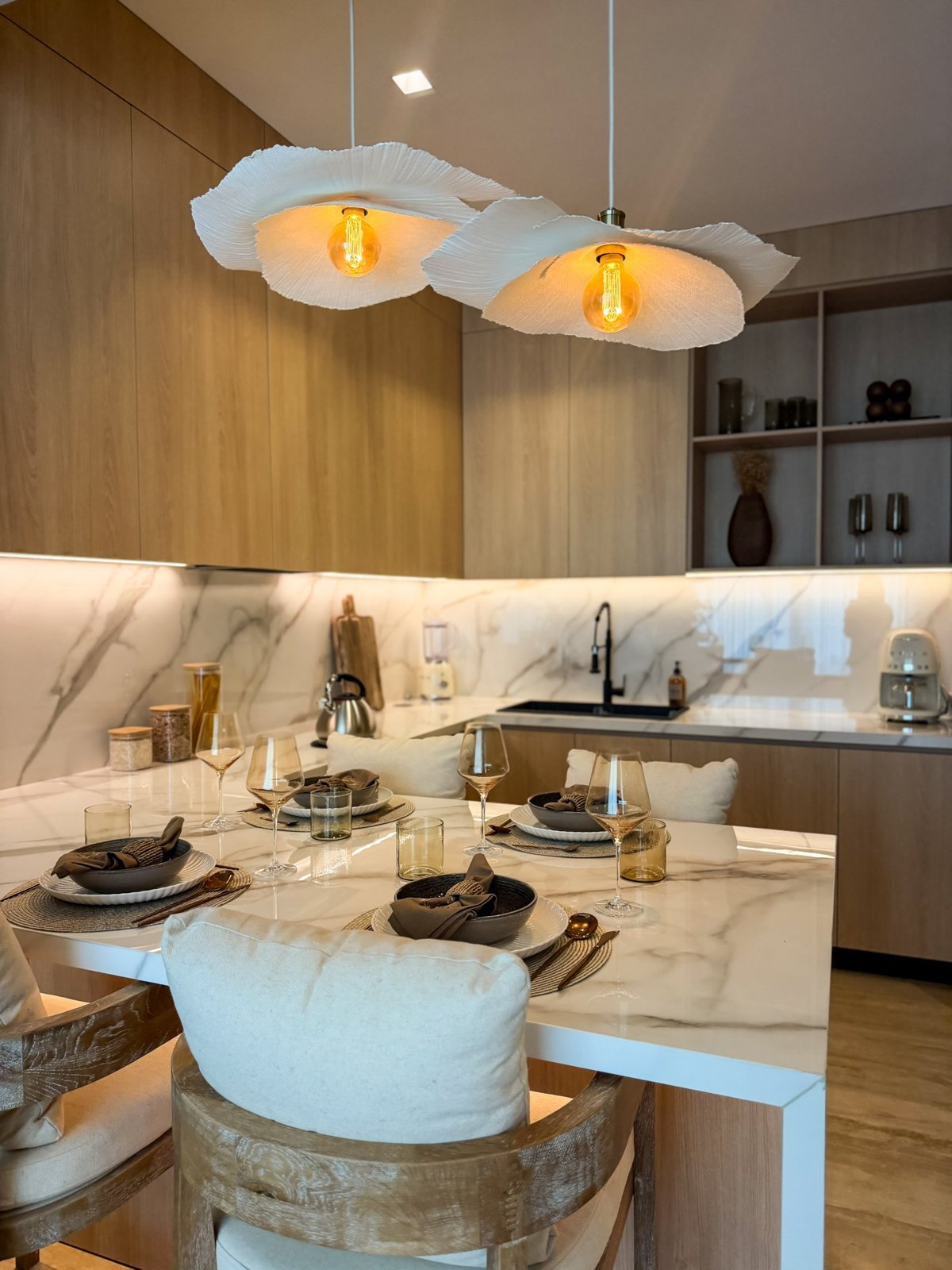 Cocina y comedor de un departamento amueblado con lámparas artesanales y cubierta de mármol